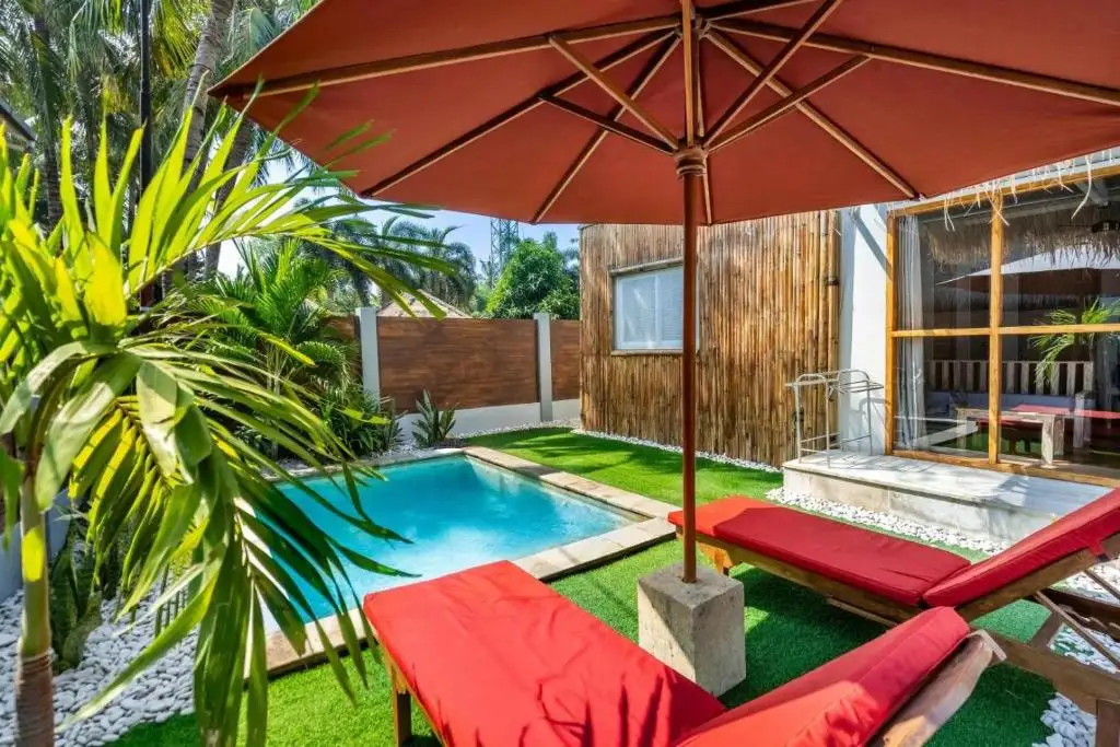 Red parasol and sun loungers by the pool
